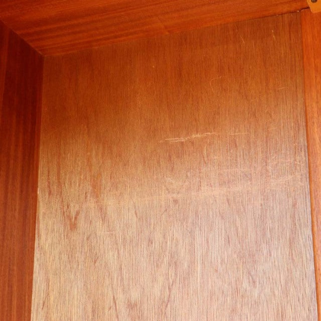 Close-up of vintage teak wood grain and smooth finish on British mid-century wardrobe by William Laurence, showcasing warm.