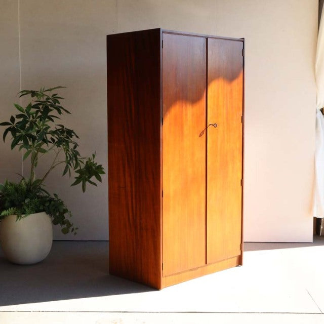 Mid-century British teak wardrobe with rich wood grain, slender handles, and clean lines, vintage Denmark style.