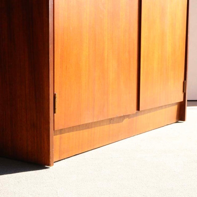 Mid-century vintage British teak cabinet with smooth wood grain and clean lines, minimal legs visible.