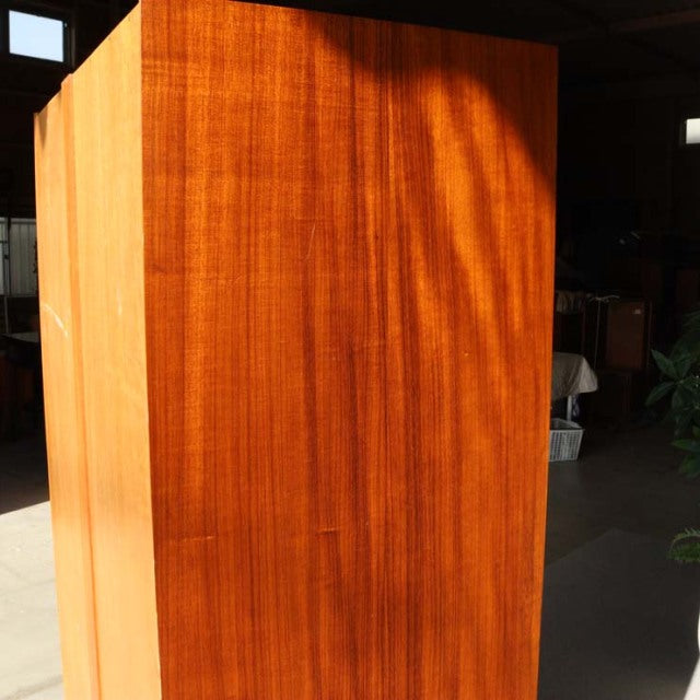 Vintage British mid-century teak cabinet with rich wood grain and smooth flat panels under natural light.