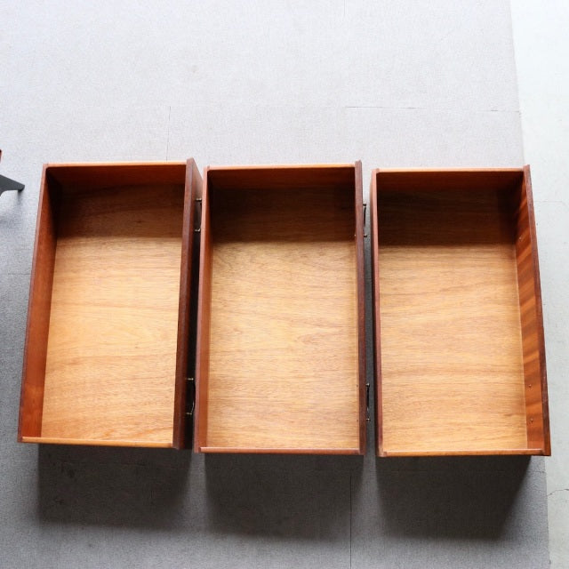 Three open drawers of mid-century British vintage teak chest by Meredew, showing smooth wood grain and warm tones.