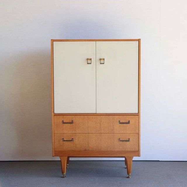 Vintage G-Plan teak cabinet with pale cream doors, two drawers, tapered legs, mid-century British design.