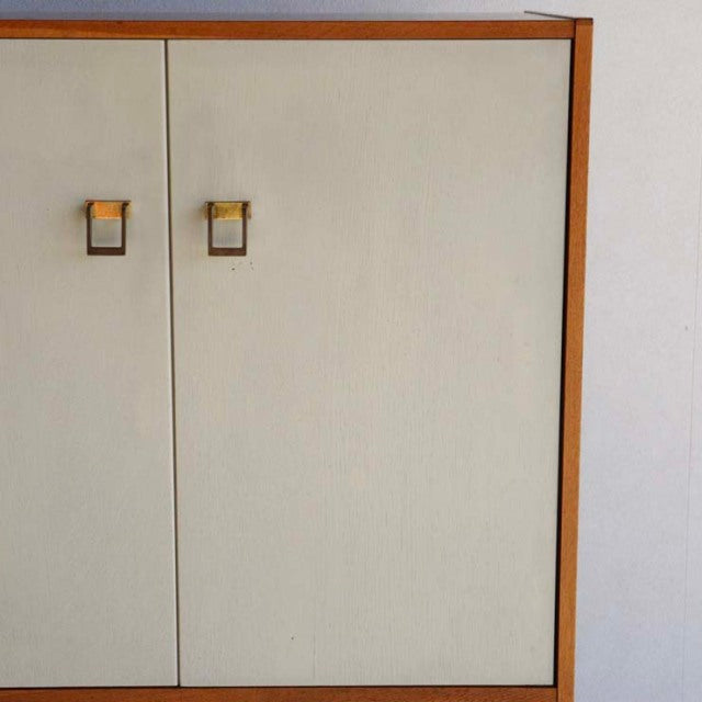 Vintage British G-Plan mid-century teak cabinet with cream laminate doors and square wooden handles, showcasing clean lines.