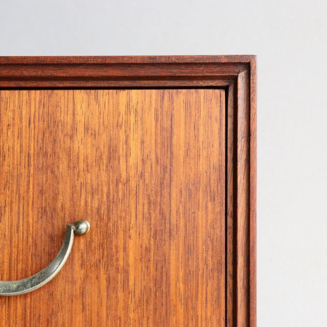 Mid-century British teak five-drawer chest by Meredew with sleek brass handles and rich wood grain detailing.