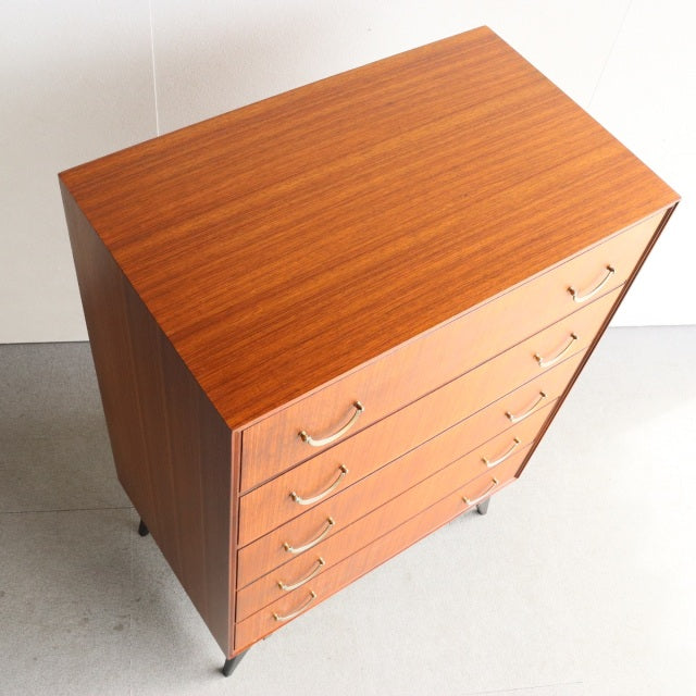 Mid-century British teak chest of drawers by Meredew with five drawers, sleek wood grain, and tapered legs.
