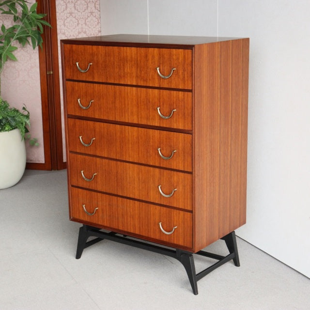 Vintage mid-century teak five-drawer chest by Meredew with British-Denmark design, visible wood grain, and black tapered legs.