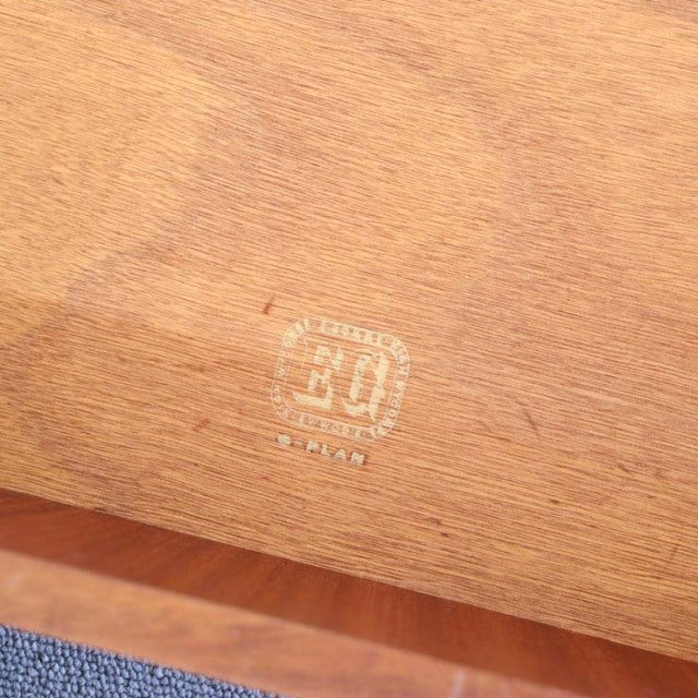 Close-up of British mid-century G-PLAN teak wood vintage cabinet showing clear G-PLAN gold stamp on smooth wood grain surface.