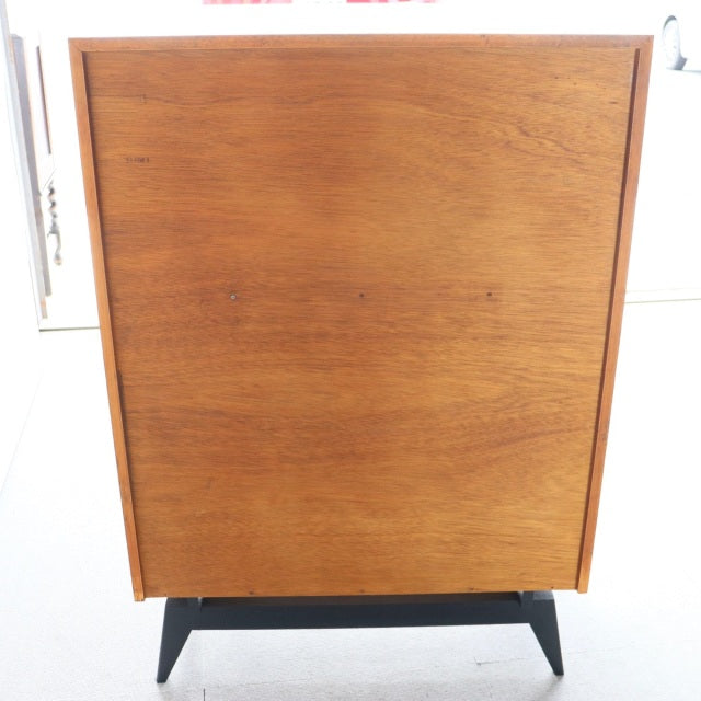 Vintage teak mid-century five-drawer chest with rich wood grain, elevated on sleek black angled legs, British design.