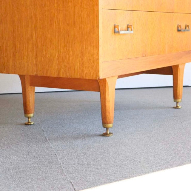 Mid-century British teak G-PLAN cabinet legs with brass caps, showcasing vintage wood grain and elegant tapered design.