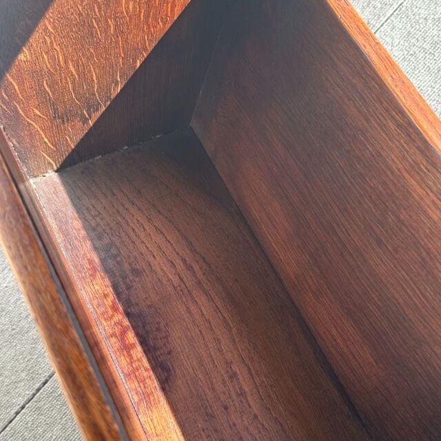 Close-up of vintage teak wood grain and interior corner of a British mid-century small antique table with warm brown tones.