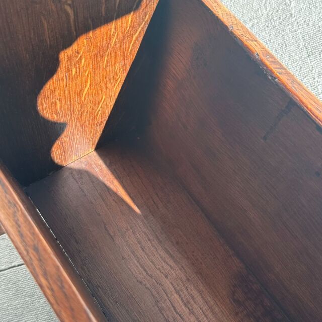 Close-up of vintage British teak wood table corner showing rich wood grain and smooth mid-century finish with curved detail.