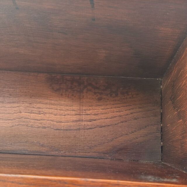 Close-up of vintage British teak wood grain inside a small mid-century oak antique table showcasing rich texture and warm.