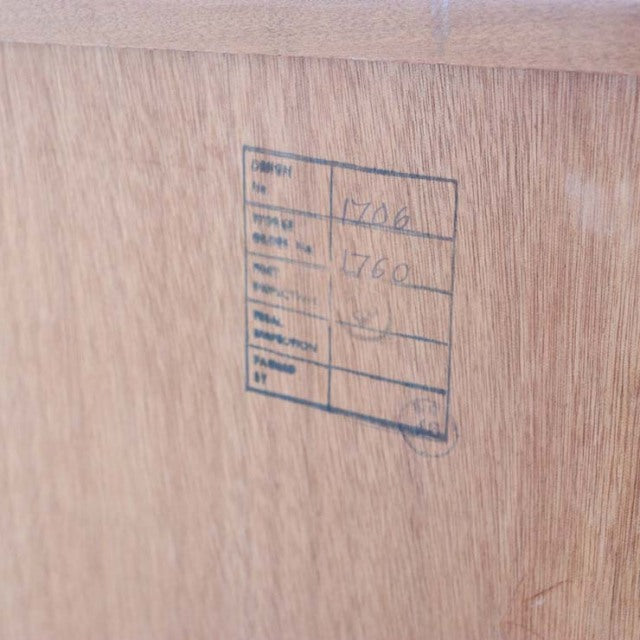 Close-up of vintage G-Plan teak wood with clear grain and mid-century British furniture label stamped on smooth oak surface.