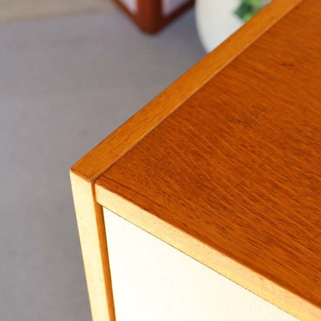 Close-up of vintage British G-Plan mid-century teak cabinet with smooth wood grain and light oak frame edges.