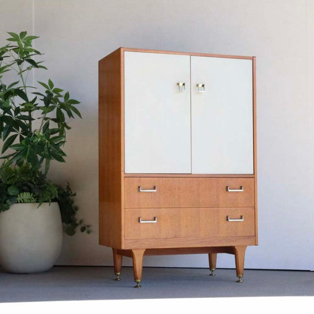 Mid-century British G-PLAN teak tallboy cabinet with white doors, wood grain finish, and tapered legs.