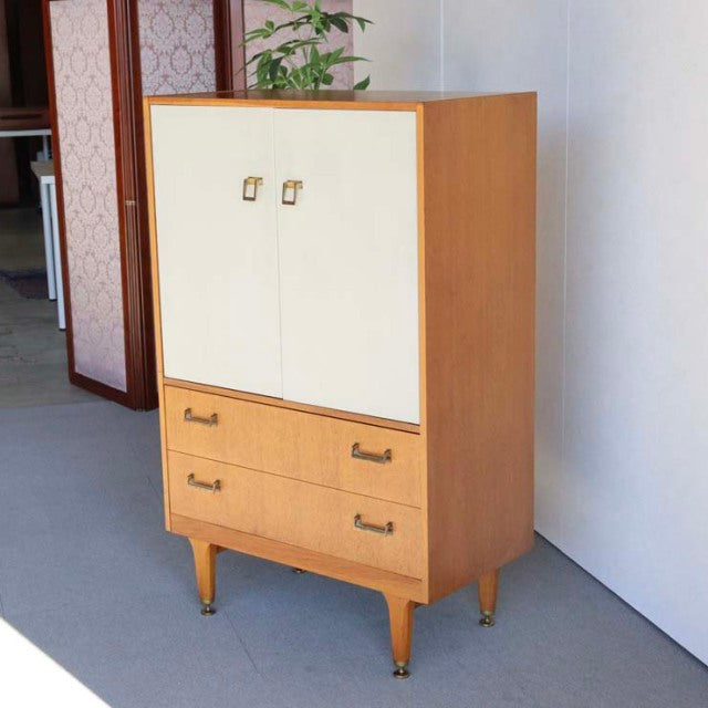 Vintage British G-Plan mid-century teak cabinet with cream double doors, two drawers, and tapered legs.