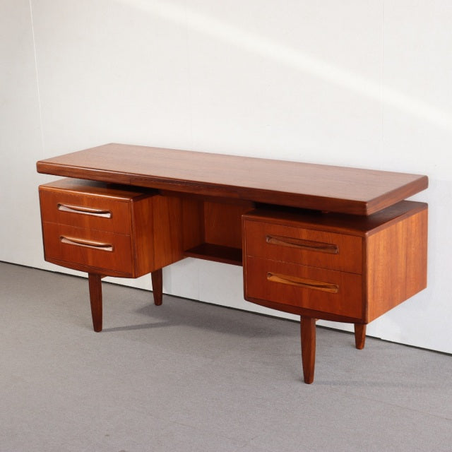 Vintage teak mid-century British G-PLAN desk with rich wood grain, tapered legs, and two spacious drawers.