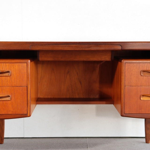 Vintage teak G-PLAN mid-century British desk with rich wood grain, rounded edges, and tapered legs, featuring six drawers.
