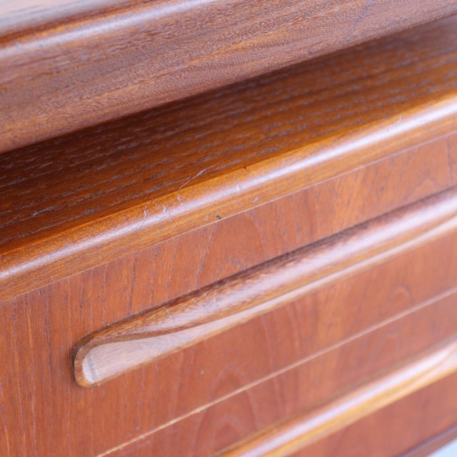 Close-up of vintage British mid-century teak desk drawer showing smooth wood grain and curved teak handle.
