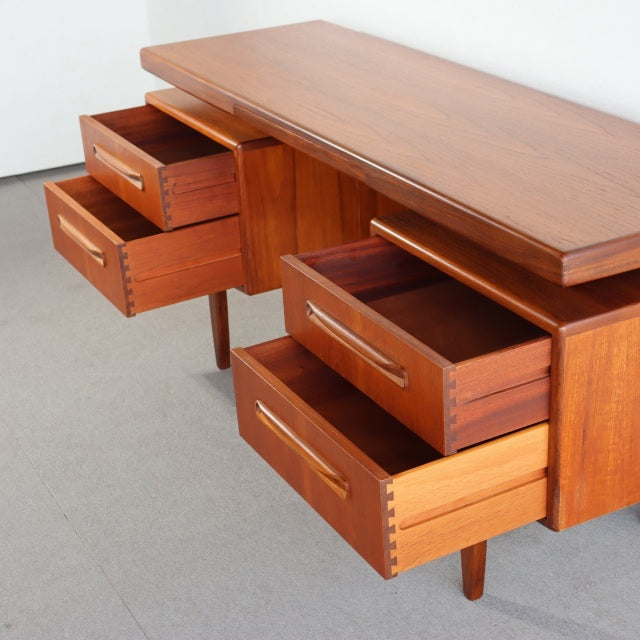 Vintage teak G-PLAN mid-century British desk with rich wood grain, tapered legs, and four open drawers showing dovetail.