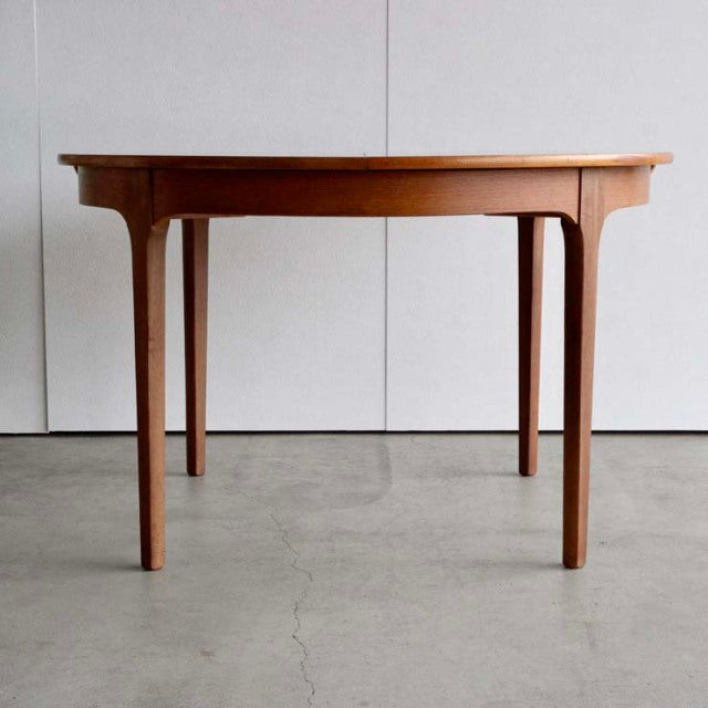 Vintage mid-century teak dining table with tapered legs, British design by NATHAN, smooth wood grain finish.