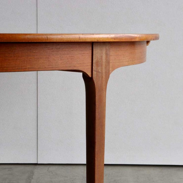 Mid-century British vintage teak dining table leg with visible wood grain and smooth rounded edge.