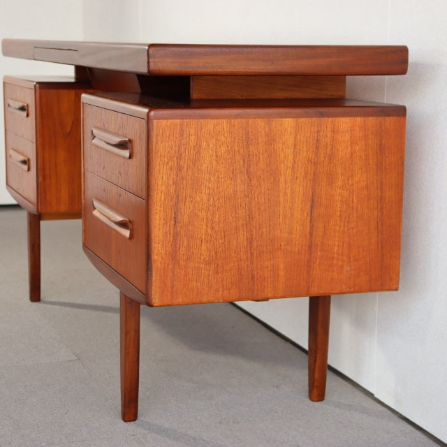 Mid-century vintage British G-PLAN teak desk with rich wood grain, slender tapered legs, and two smooth drawers on each side.