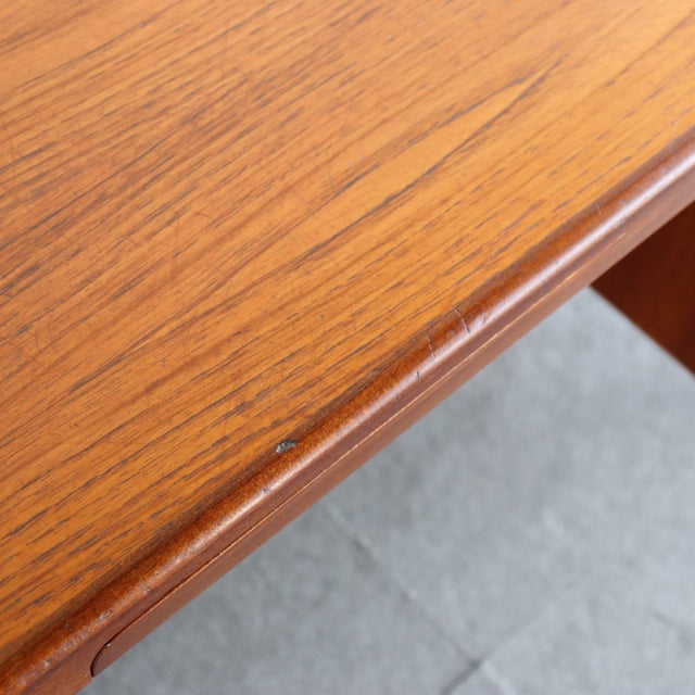 Close-up of vintage teak wood desk surface showing warm grain and smooth mid-century British craftsmanship.