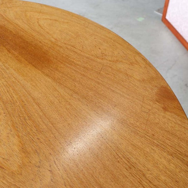 Mid-century British vintage teak dining table with smooth oval top and visible wood grain.