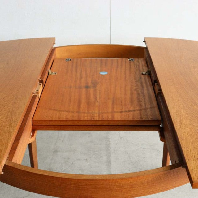 Mid-century British vintage teak dining table by NATHAN with open extension leaf, smooth wood grain, and tapered legs.