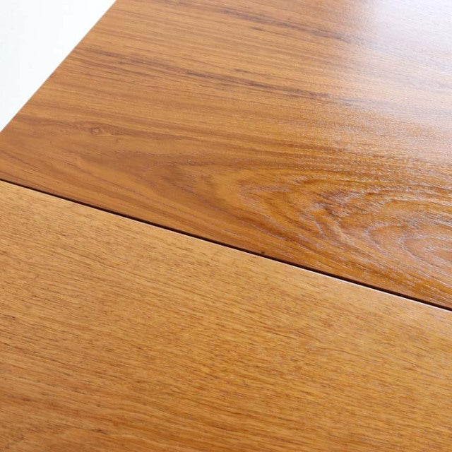 Close-up of vintage teak dining table top with smooth grain and mid-century British design details.