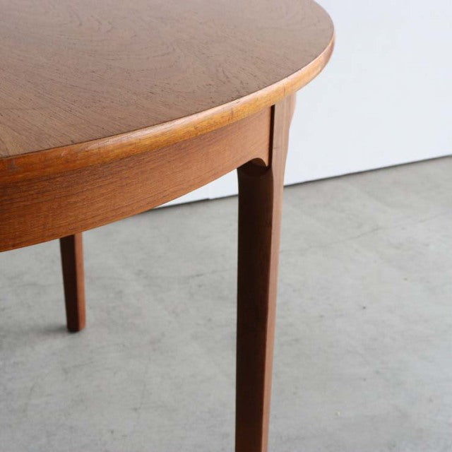 Mid-century vintage British teak dining table with oval top and slender tapered legs showing smooth wood grain.