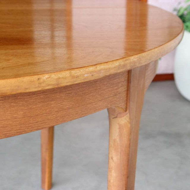 Mid-century British vintage teak dining table with smooth wood grain, rounded edge, and tapered legs from Denmark.