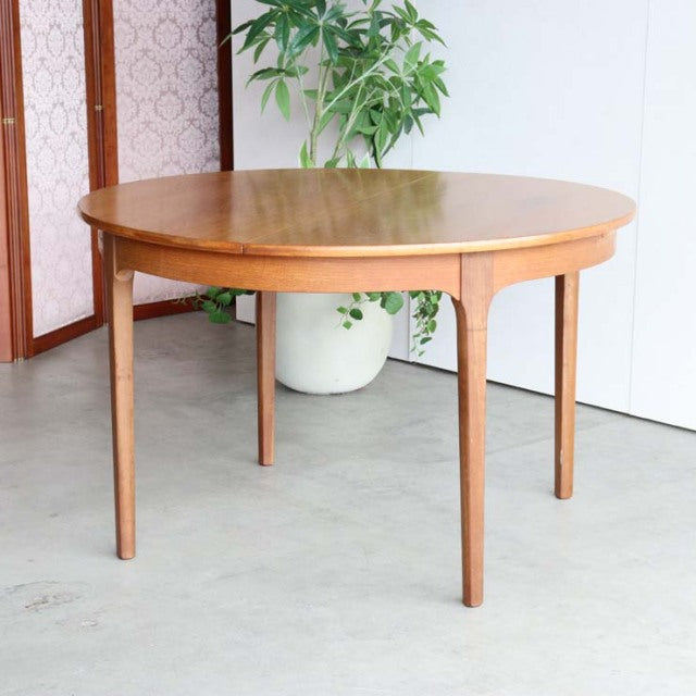 Vintage teak round dining table with tapered legs, smooth wood grain, mid-century British-Denmark design.