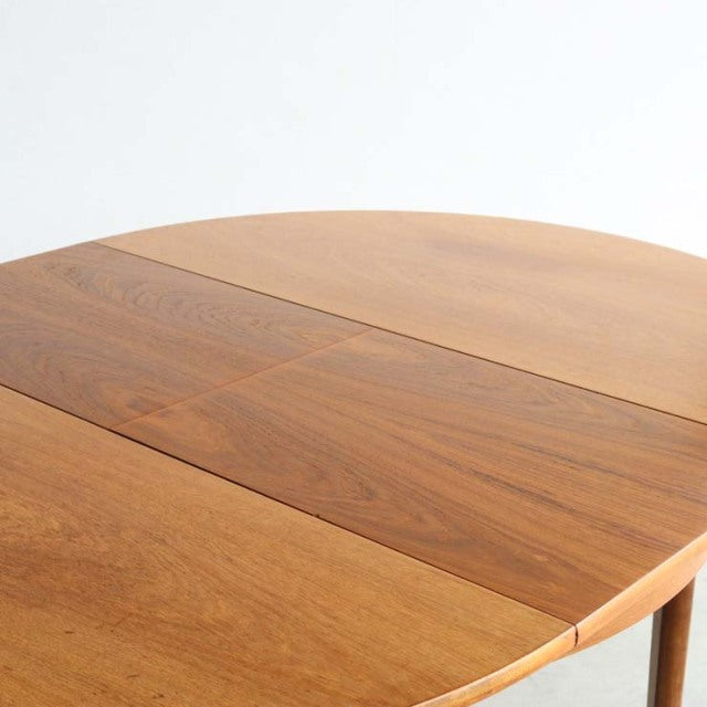 Vintage teak mid-century British dining table with smooth oval top and elegant rounded edges.