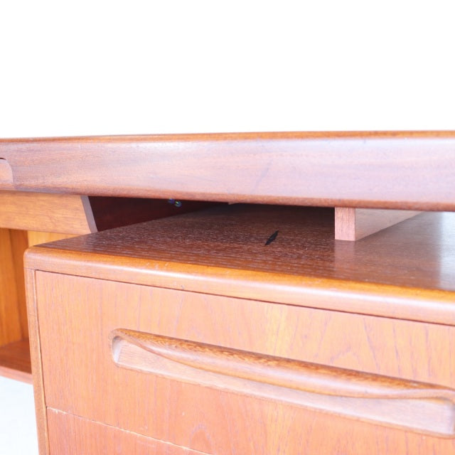Mid-century British G-PLAN teak desk with smooth wood grain, sculpted drawer handles, and clean lines.