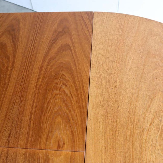 Close-up of vintage teak dining table with rich wood grain and smooth, curved edges, mid-century British design.