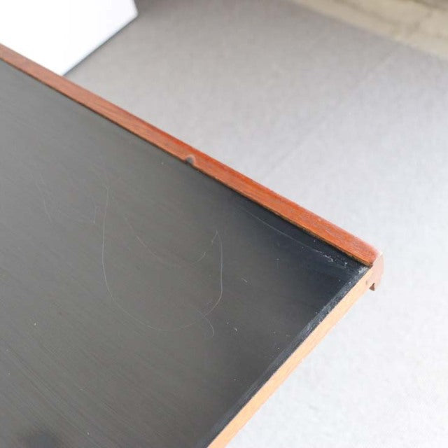 Corner detail of vintage McIntosh mid-century teak coffee table with black top and visible wood grain.
