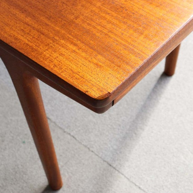 Vintage McIntosh teak coffee table corner showing rich wood grain and rounded mid-century British design legs.