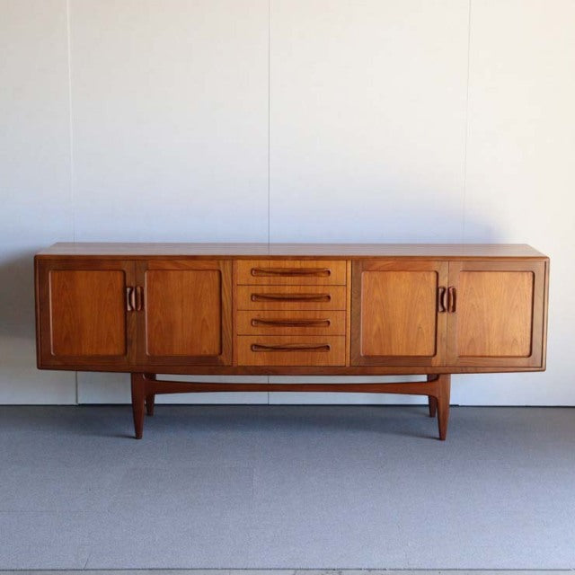 British mid-century G-Plan teak sideboard with rich wood grain, four central drawers, two side cabinets, and tapered legs.