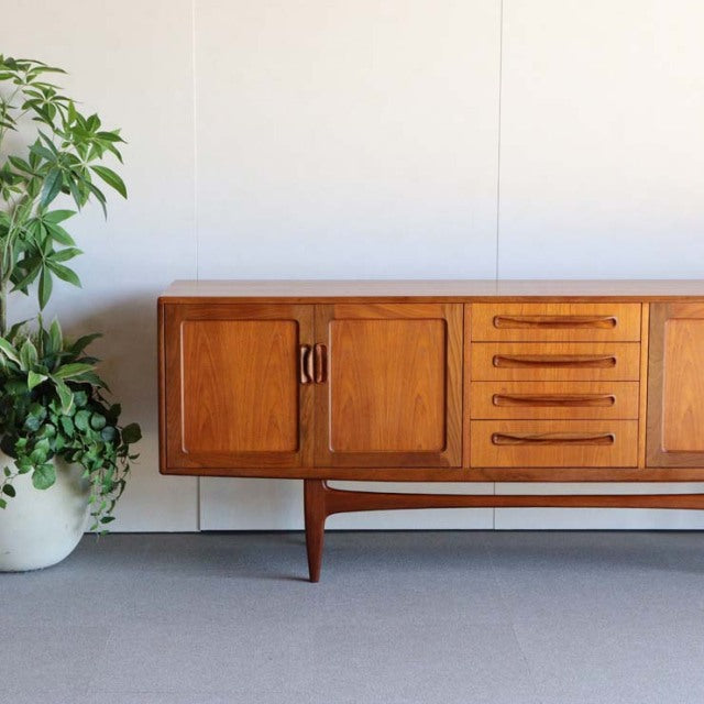 Mid-century vintage British teak sideboard by G-PLAN with warm wood grain, four drawers, two cabinet doors, and tapered legs .