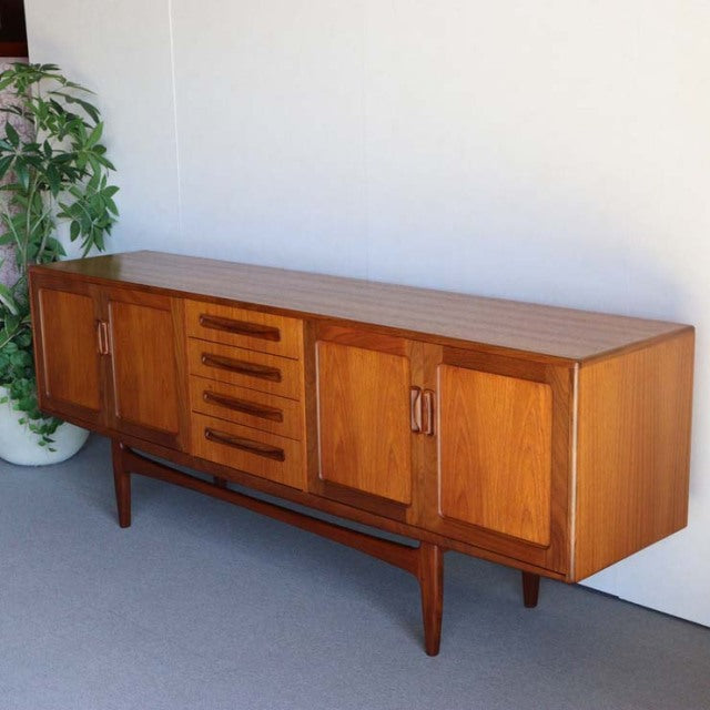 Mid-century British G-PLAN Fresco teak sideboard with rich wood grain, tapered legs, and central drawers flanked by cabinets.