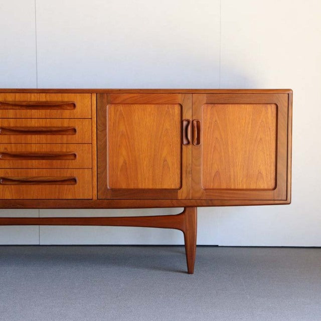 British vintage mid-century teak sideboard by G-PLAN with smooth wood grain, curved handles, and tapered legs.