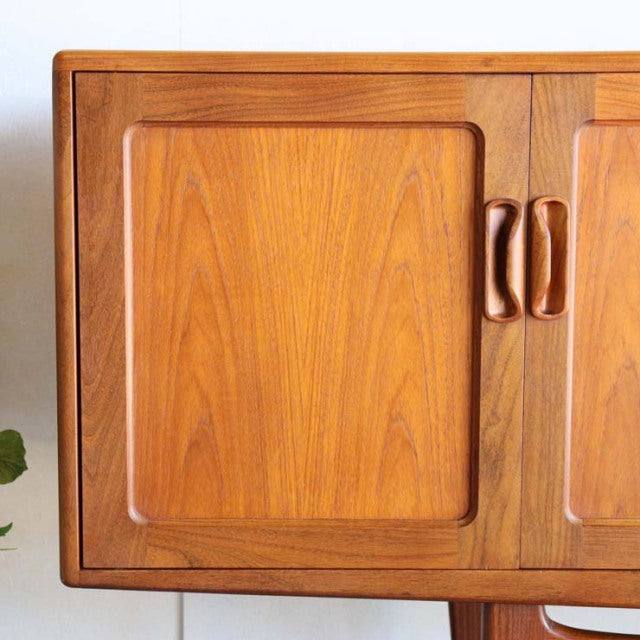 Mid-century British vintage G-PLAN teak sideboard with smooth wood grain, curved wooden handles, and clean rectangular doors.