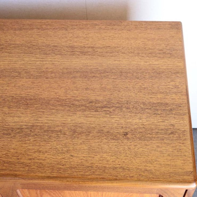 Close-up of vintage British mid-century teak sideboard top showing smooth wood grain and warm honey tones.