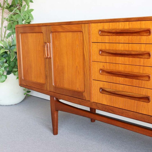 Mid-century British vintage G-PLAN Fresco teak sideboard with smooth wood grain, curved handles, and tapered legs.