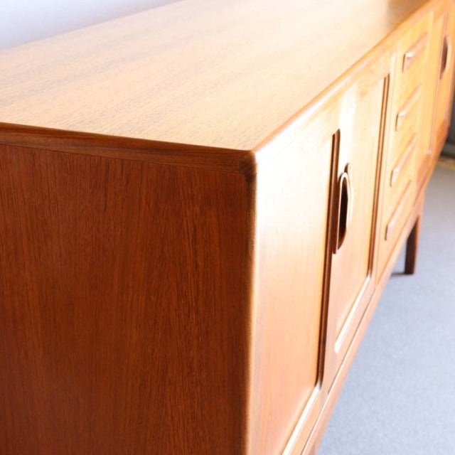 Mid-century British G-Plan Fresco teak sideboard with smooth wood grain, rounded edges, and tapered legs in Denmark style.