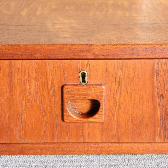 Close-up of teak vintage mid-century cabinet drawer with integrated curved handle and brass keyhole, showcasing Danish wood.