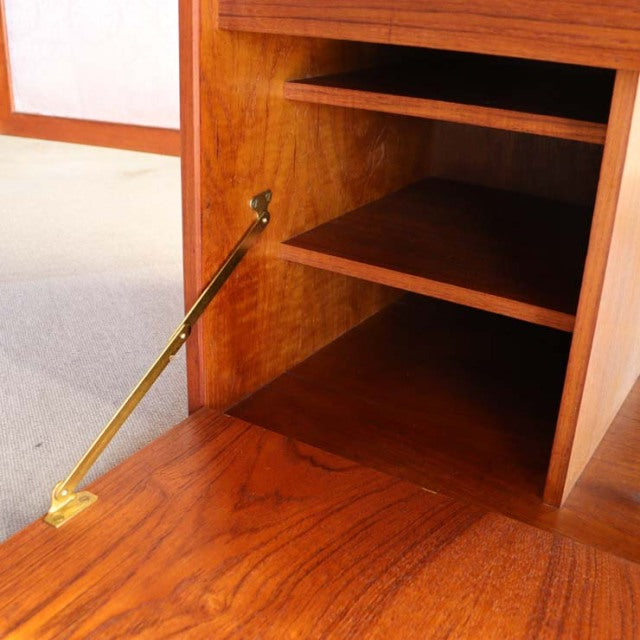 Mid-century teak cabinet with warm wood grain, brass hinge, and open shelf by Danish brand PS system Preben Sørensen.