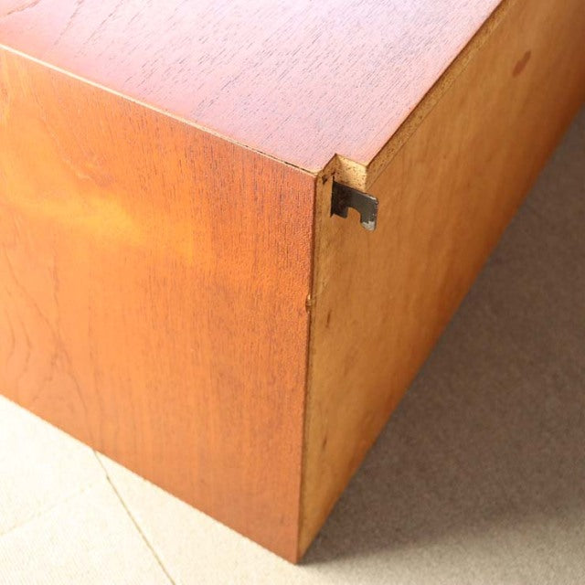 Mid-century Danish teak cabinet corner showing rich wood grain, clean lines, and brass hardware detail.